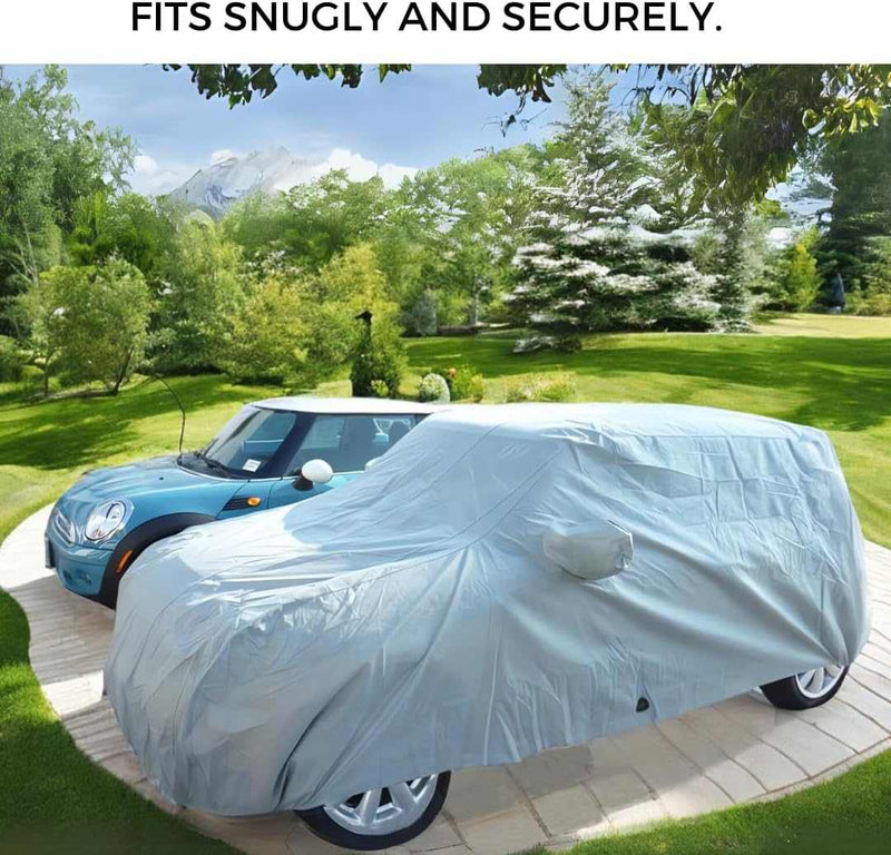 A car draped in a Formosa Covers heavy-duty car cover, designed specifically for the Mini Cooper Hardtop 2 Door and 4 Door models, Convertible, and Coupe—all fitting up to 158"L—rests on the driveway beside a blue Mini Cooper. In the backdrop, lush greenery and distant mountains stand majestically beneath a clear sky.