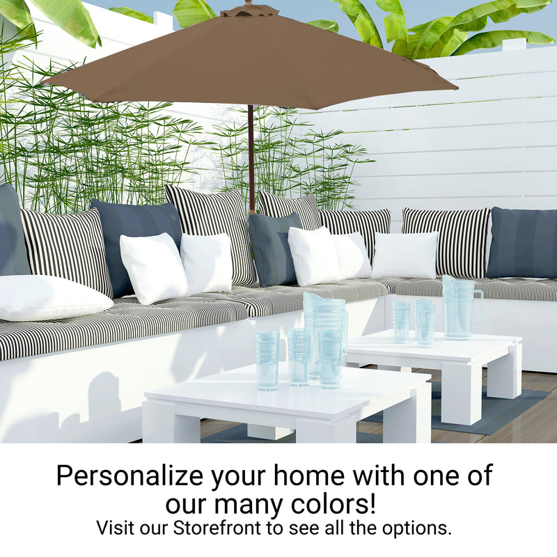 Create a stylish outdoor seating area featuring our 9ft Market Patio Umbrella with an 8 Rib Replacement Canopy in Carmel Latte by Formosa Covers. Complement it with a white and gray sectional sofa adorned with striped and solid pillows, and two sleek white tables topped with translucent plastic glasses. Green foliage and a white fence provide a serene backdrop. Text reads, "Personalize your home with one of our many colors! Visit our Storefront to see all the options.