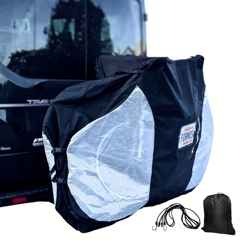 A Formosa Covers Lightweight Quad Bike Rack Cover for Transport (Fits 3-4 Bikes) in extra large, with translucent ends, is secured at the back of a black vehicle's hitch mount bike rack. The cover provides UV and water damage protection, displays a logo, and comes with several black bungee cords and a small black storage bag. The vehicle appears to be parked outdoors.