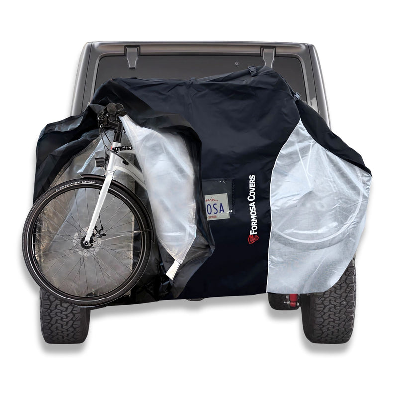 A vehicle with a hitch mount bike rack has a bicycle covered by the Lightweight Quad Bike Rack Cover for Transport from Formosa Covers. The partially open cover, in black and gray with translucent ends, reveals the bicycle attached to the hitch. Providing UV and water damage protection, this extra-large cover fits 3-4 bikes.