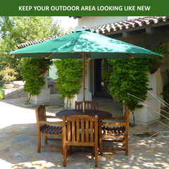 A patio area featuring a durable wooden table and chairs set under the Formosa Covers 11ft Market Patio Umbrella Double-Vented 8 Rib Replacement Canopy in Hunter Green. The patio is surrounded by lush greenery and shaded by a tiled roof. The text 