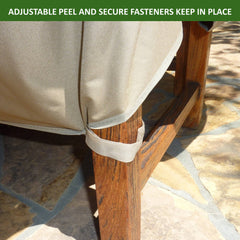 Close-up of a corner of Formosa Covers' Patio Outdoor Large Loveseat Bench Cover, Classic Taupe, secured using adjustable hook-and-loop fasteners. The beige cover is strapped around a wooden chair leg, ensuring durability with its heavy-duty vinyl backing. The background features a stone patio. Text at the top reads, 